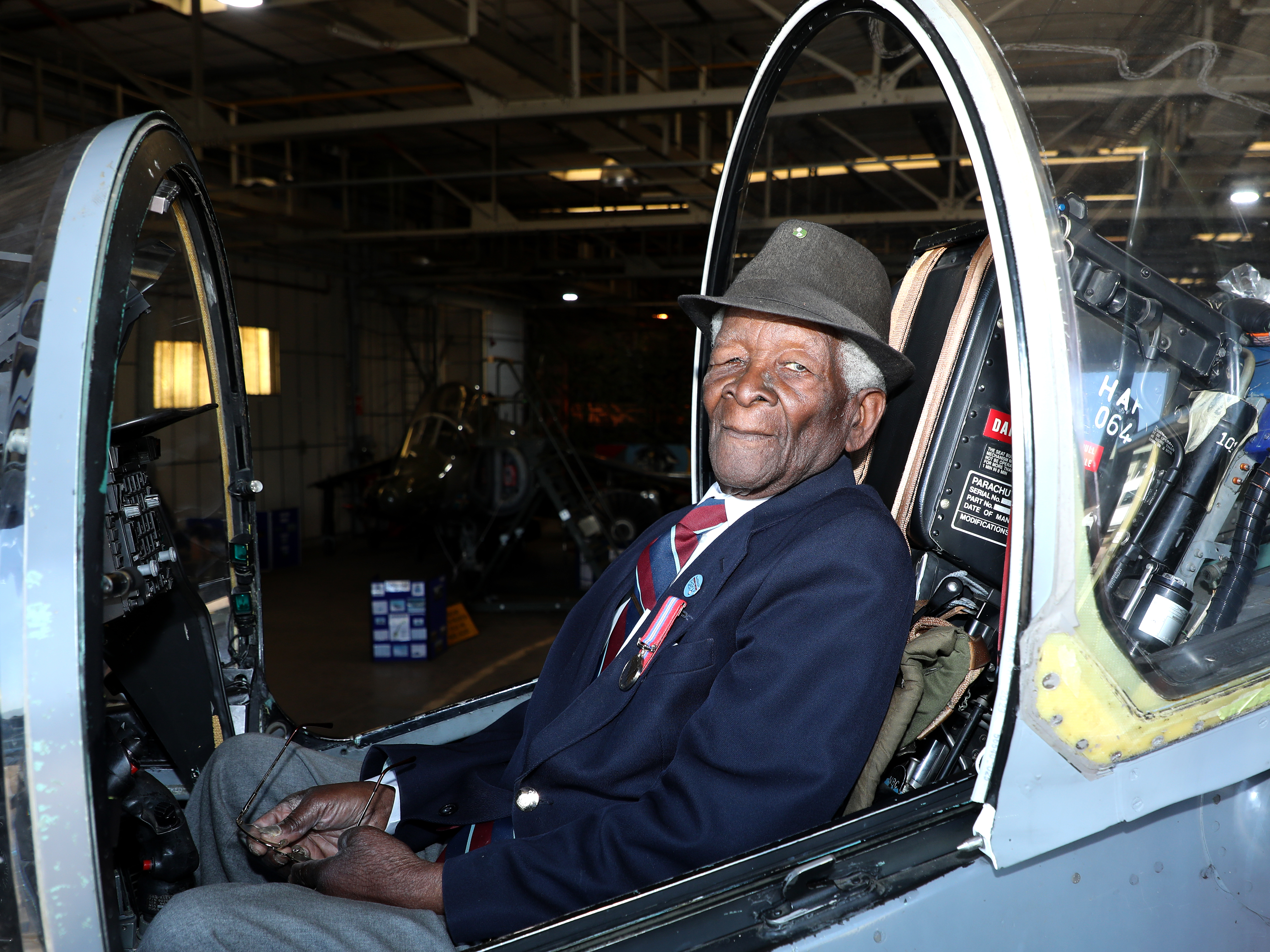 Image shows veteran in the cockpit of an aircraft inside a hangar.